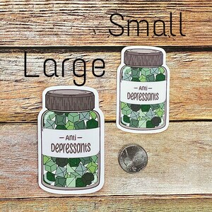May include: Two stickers, labeled "Large" and "Small", depict jars filled with green and gray geometric shapes. The labels on the jars read "Anti-Depressants". A quarter is next to the smaller jar. The background is a wooden surface.