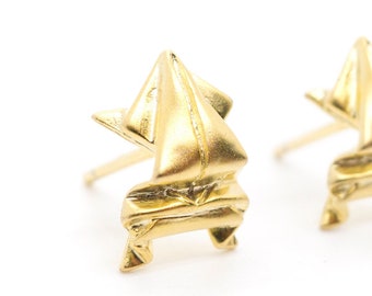 May include: A pair of gold origami-style earrings. The earrings are made of folded metal and have a geometric design.