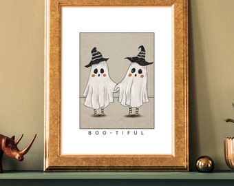 May include: A framed print with a whimsical illustration of two ghosts wearing witch hats. The ghosts are white with black eyes and mouths. The text "BOO-TIFUL" is printed below the ghosts.