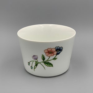 Puede incluir: Taza de cer&aacute;mica blanca con un dise&ntilde;o floral con flores rosas, azules y moradas con hojas verdes.