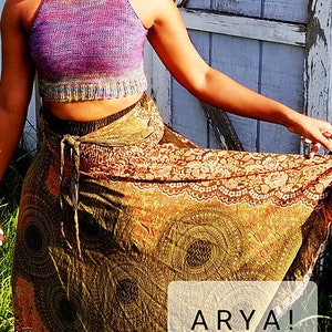 May include: A woman wearing a purple and green halter top with a brown and gold patterned skirt. The skirt has a floral design and the text "ARYA!" is visible in the bottom right corner of the image.