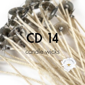 May include: A close-up of a pile of white cotton candle wicks with metal bases. The wicks are labeled "CD 14 candle wicks".