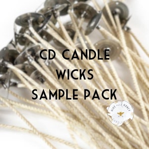 May include: A close-up of a sample pack of CD candle wicks. The wicks are white and have a metal base. The pack is labeled "CD Candle Wicks Sample Pack" and features a logo for "Hive and Honey Candle Co."