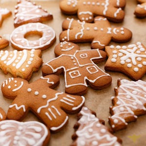 May include: Assortment of gingerbread cookies decorated with white icing. The cookies are shaped like trees, stars, gingerbread people, and a wreath.