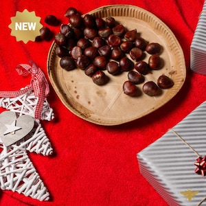 Peut inclure: Une assiette de châtaignes grillées sur un fond rouge avec une décoration de Noël en forme de cœur blanc et un coffret cadeau emballé. L'assiette est en papier brun et a un motif en forme d'étoile. Le coffret cadeau est emballé dans du papier rayé gris et blanc avec un nœud rouge. Le texte "NEW" est sur une étoile jaune.