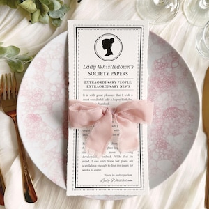 Pretty Dear Gentle Reader Ton Birthday Tea Society announcement wrapped in a pink ribbon on a plate sitting on a silk white background with gold fork and knife