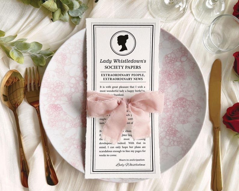 Pretty Dear Gentle Reader Ton Birthday Tea Society announcement wrapped in a pink ribbon on a plate sitting on a silk white background with gold fork and knife
