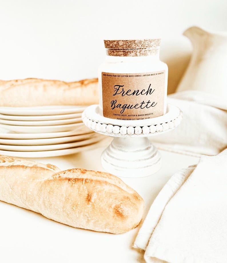 May include: A white ceramic mug with a black handle and the text "But First, Coffee" in a black, handwritten-style font. The mug is on a white surface.