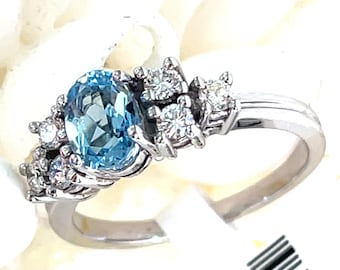 May include: A silver ring with a light blue oval gemstone surrounded by smaller clear gemstones.