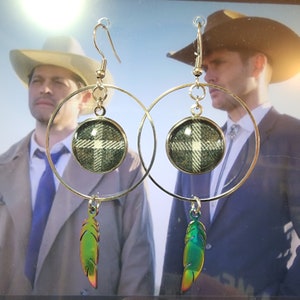 a pair of silver hoop earrings with green and blue feathers