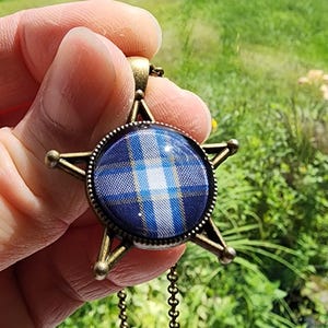 Collar de Supernatural hecho con un estampado a cuadros de Sam Winchester "Demon Thrashing" fiel a la pantalla. Estrella de bronce a cuadros verdes y azules.