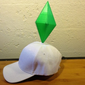 May include: A white baseball cap with a green diamond-shaped object on top.