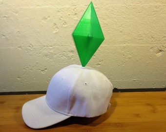 Puede incluir: Una gorra de béisbol blanca con un objeto verde en forma de diamante en la parte superior.
