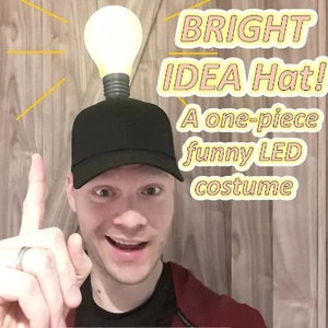 May include: A black baseball cap with a light bulb on top. The light bulb is lit and the cap has the text "BRIGHT IDEA Hat! A one-piece funny LED costume" on it.