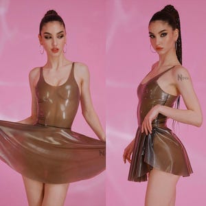 May include: A semi-transparent brown latex dress featuring a sleeveless scoop neckline bodice and a flared skirt. The garment has a glossy finish and a fitted silhouette. The word Nova is printed in small letters on the lower side of the skirt.
