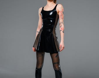 May include: A black sleeveless latex dress with a scoop neckline and a flared skirt, paired with sheer black tights and black platform boots. The dress features a glossy finish and a fitted bodice that transitions into a wider skirt silhouette.