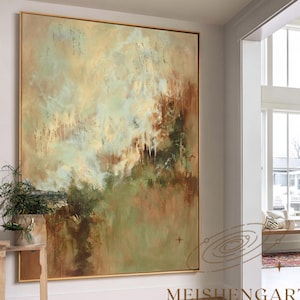 Op de afbeelding: Groot abstract schilderij in een gouden lijst. Het kunstwerk toont een mix van aardetinten, waaronder groen, bruin en crème, waardoor een textuurrijk, naturalistisch effect ontstaat. Het schilderij hangt in een lichte, moderne entree met hardhouten vloeren.