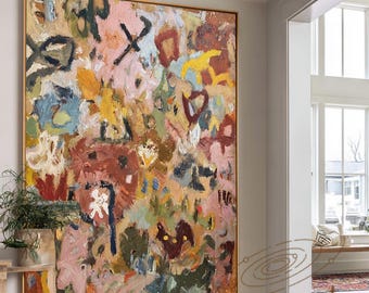 May include: Large abstract painting with a gold frame. The artwork features a mix of colors including pink, yellow, blue, and brown. The painting hangs on a white wall in a well-lit entryway with hardwood floors.