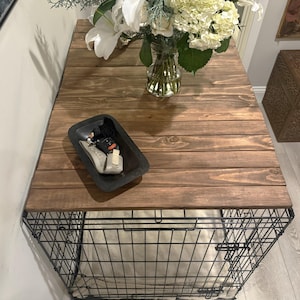 Peut inclure: Une caisse pour chien avec un plateau en bois brun fonc&eacute;. Un plateau noir avec divers objets est pos&eacute; sur le dessus, et un vase de fleurs blanches et de verdure est &eacute;galement pr&eacute;sent. La caisse a un cadre en fil de fer.