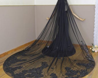 May include: A black tulle wedding veil with floral embroidery. The veil is long and flowing, with a delicate lace pattern.