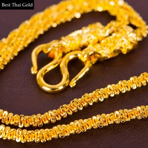 May include: A gold chain necklace with a detailed, intricate design. The chain is made of small, linked circles and has a hook clasp.