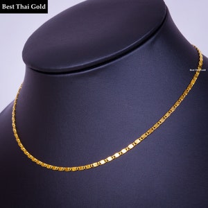 May include: A gold chain necklace featuring a series of interconnected, flat, oval-shaped links with a polished finish. The text 'Best Thai Gold' is visible in the upper left corner and on the right side of the chain.