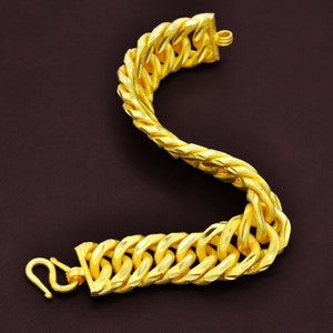 May include: A gold chain bracelet with a thick, twisted design. The bracelet has a clasp closure.