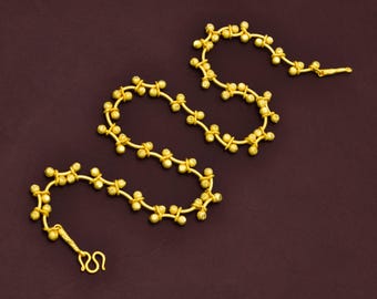 May include: A gold chain necklace with a delicate design featuring small round beads connected by thin links. The necklace is made of multiple strands, creating a layered effect.