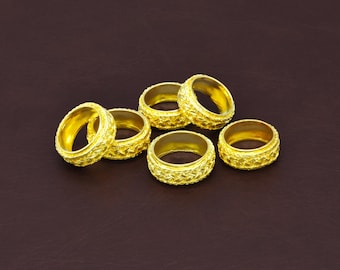 May include: A collection of five gold-colored rings, each featuring a textured, braided pattern around the outer band. The rings have a polished, reflective finish and are arranged in a cluster, showcasing their uniform design and metallic luster.