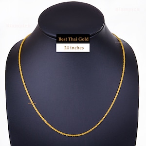May include: A gold chain necklace on a black display stand. The chain is 24 inches long and has a delicate, braided design. The text "Best Thai Gold" is printed on a white label.