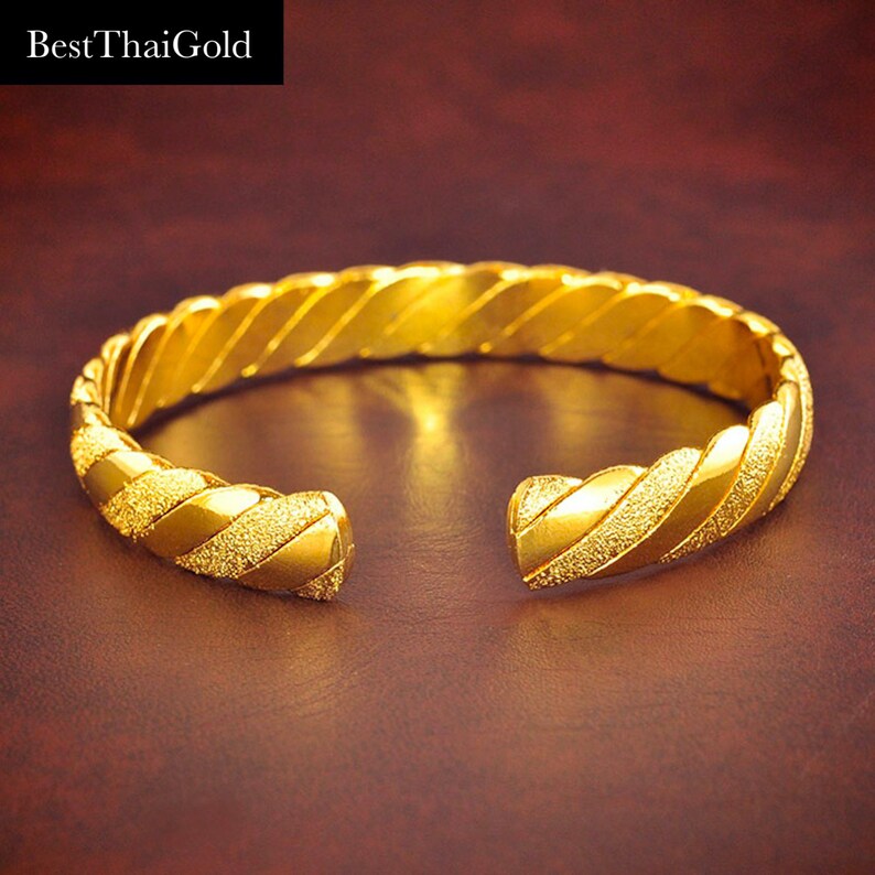 May include: A gold bangle bracelet with a twisted design and a textured finish.