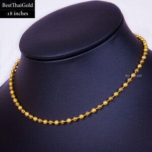Pu&ograve; includere: Una collana a catena con sfere dorate lunga 18 pollici. La collana &egrave; composta da un'alternanza di sfere d'oro lisce e lucide e sfere d'oro testurizzate con finitura opaca. Il testo BestThaiGold &egrave; visibile nell'angolo in alto a sinistra.