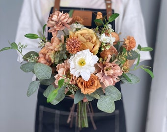 Könnte beinhalten: Ein Strauß künstlicher Blumen in Braun- und Weißtönen. Der Strauß enthält Rosen, Nelken und Grün.