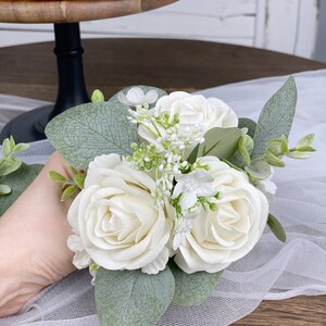 Op de afbeelding: Een klein boeket met witte rozen en groen, perfect voor een bruiloft of speciale gelegenheid.