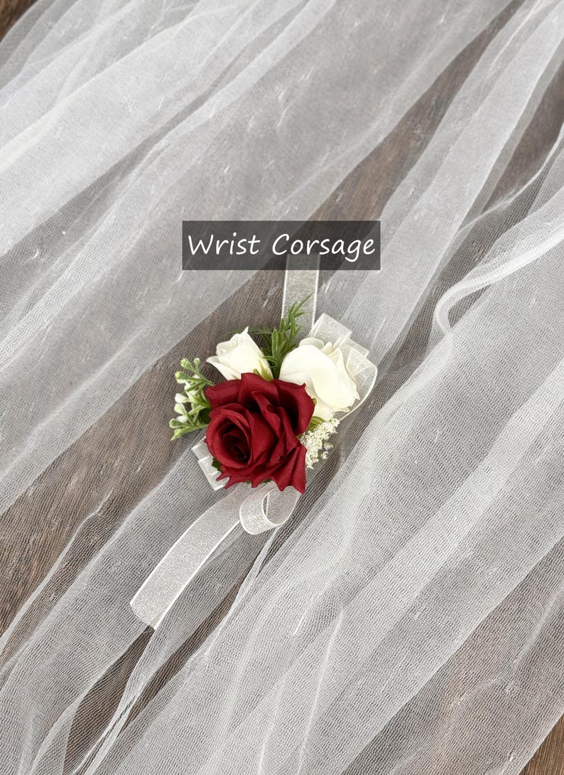 May include: A red and white wrist corsage with a white ribbon. "Wrist Corsage" is written in black text on a white background.