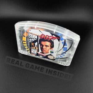 May include: A clear plastic protective case containing a GoldenEye 007 video game cartridge for the Nintendo 64 console. The label features a portrait of a man holding a gun, the title text GoldenEye 007, and an ESRB Teen rating symbol.