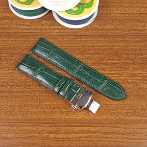 Può includere: Due cinturini per orologio in pelle verde con fibbia argentata. I cinturini hanno un motivo a coccodrillo.