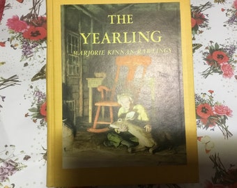 The Yearling- written by Marjorie Kinnan Rawlings- hardcover 1961. A fawn found alive by it's dead mother  is adopted by a Florida family.