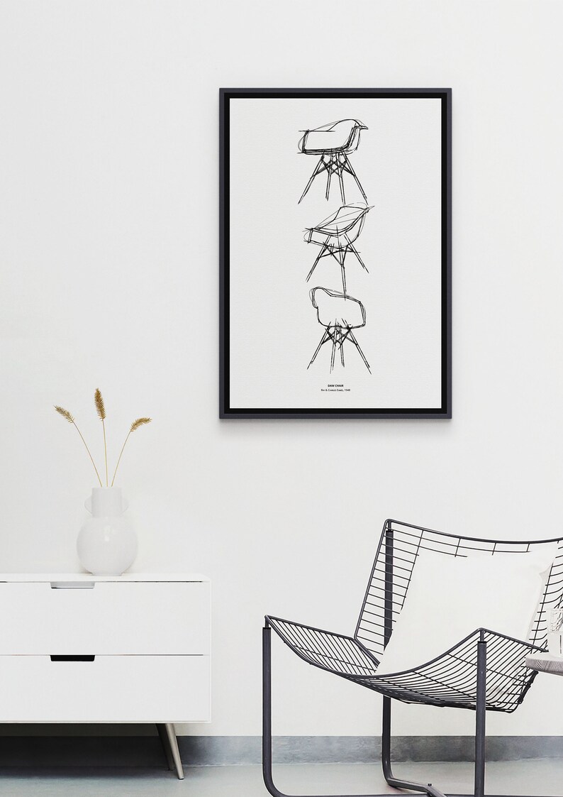 May include: A black and white line drawing of a chair, repeated three times in a vertical stack. The drawing is framed in a black frame and hung on a white wall. The text "Eames Chair" is printed below the drawing.