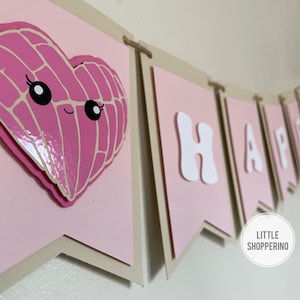 May include: A pink and brown banner with the word "HAPPY" in white letters. The first flag has a pink heart with a face on it.