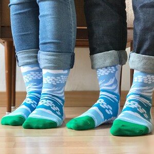 Könnte beinhalten: Ein Paar blaue Socken mit einem weißen und blauen Wellenmuster. Die Socken haben einen grünen Saum oben.