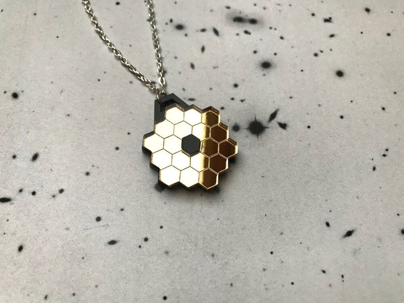May include: A gold and black honeycomb pendant necklace. The pendant is made of a shiny metal and has a geometric design.