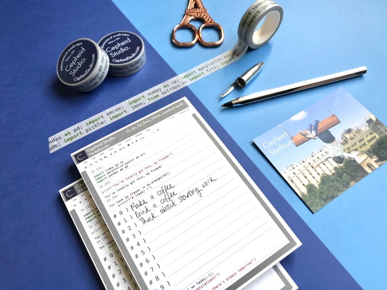 Pu&ograve; includere: Una pila di quaderni a righe grigi e bianchi con un bordo grigio. Il quaderno in cima ha note scritte a mano in inchiostro nero che dicono "Make a coffee", "Drink a coffee", e "Think about starting work". I quaderni hanno il testo "Cepheid Studio" stampato sulla copertina.