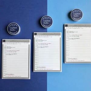 Pu&ograve; includere: Tre blocchi note bianchi con bordi grigi e il testo "Cephheid Studio" stampato in alto. I blocchi note sono progettati per scrivere codice e hanno righe per scrivere e sezioni numerate per organizzare il codice. I blocchi note sono su uno sfondo blu.