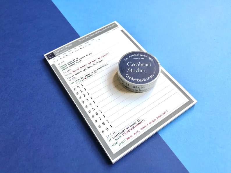 Pu&ograve; includere: Un blocco note grigio e bianco con un frammento di codice in bianco e nero e righe numerate. Un dispenser di nastro washi argentato e blu con il testo "Cepheid Studio" &egrave; sul blocco note. Il nastro washi &egrave; di 15 mm x 10 m.