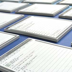 May include: A stack of lined notebooks with a gray cover and the text "Cepheld Studio Notebooks" printed on the front. The top notebook has code written on it.