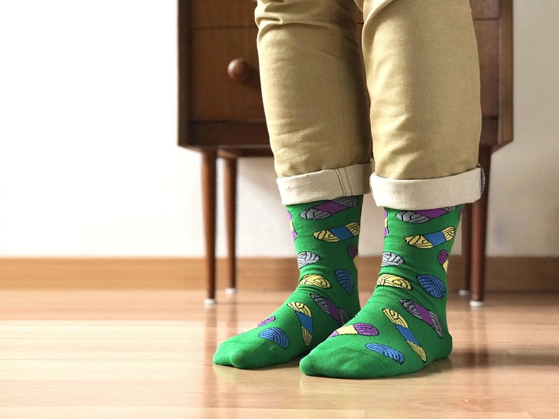 May include: A pair of green socks with a colorful pattern of abstract shapes. The socks are made of a soft, comfortable material and are perfect for everyday wear.