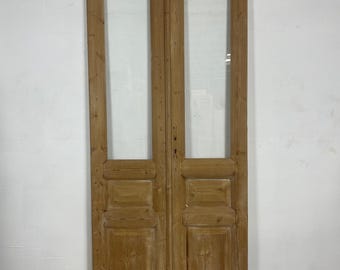 May include: A pair of antique wooden doors with glass panels. The doors are made of light brown wood and have a simple design. The glass panels are clear and allow light to pass through.
