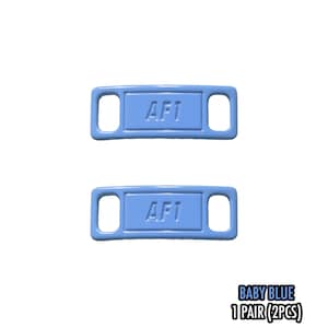 May include: Two baby blue AF1 shoe tags. Each tag has a rectangular center with rounded corners and the letters "AF1" in white. The tags have a hole on each end. The text "BABY BLUE 1 PAIR (2PCS)" is in the bottom right corner.