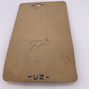 May include: A brown cardboard backing card with a hole at the top for hanging. The card has handwritten text that says "228" and "-UZ-"